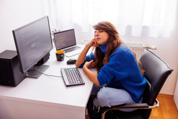 Female software developer taking a power nap at her desk while working overtime