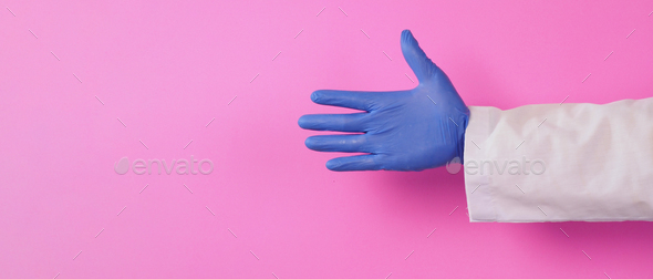 Doctor hands wear purple latex glove on pink background.He wear long sleeve gown.Empty hand