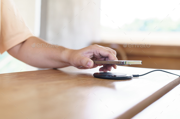 Charging mobile phone battery with wireless charging device in the table. Smartphone charging