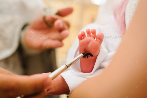 Baptism ceremony of a baby. Close up of tiny baby feet, the sacrament of baptism.The godfather holds