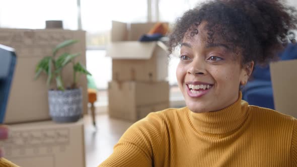 Woman Holding Keys With Mobile Phone Moving Into New Home Making Video Call Surrounded By Boxes