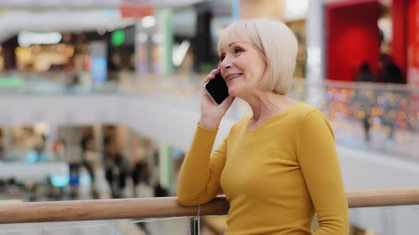 Mature Happy Woman Speaks Friendly on Phone Answers Call Communicates with Family Using Smartphone alt