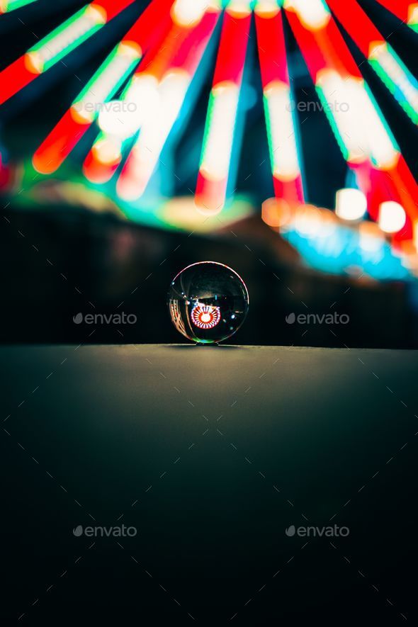 Vibrant night scene featuring the colorful lights of a Ferris wheel, visible through a clear sphere
