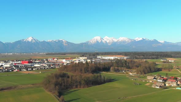 Aerial view flying up over the town of Skofja Loka in Slovenia with Alp mountains opening in the bac alt