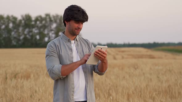 Man Farmer Using Digital Tablet Computer Standing in a Wheat Field and Using Apps and Checking alt