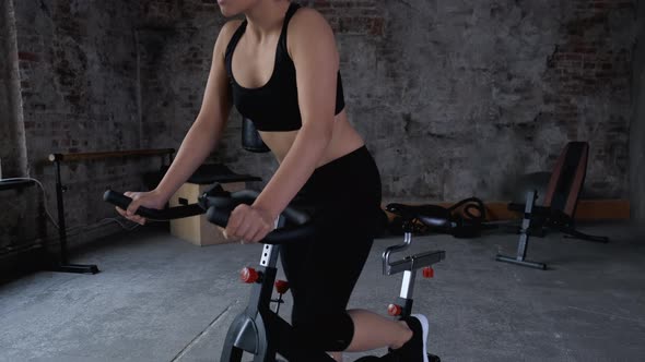 Smiling sports woman enjoying cycling at gym having positive emotion. Joyful happy athletic 