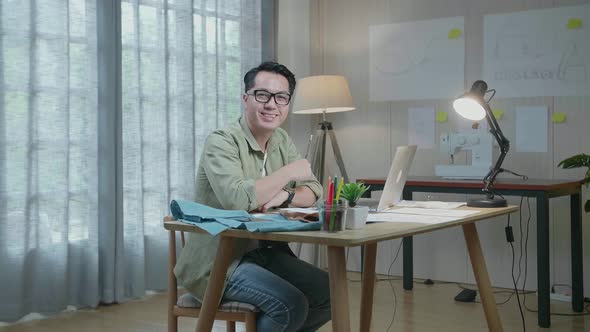 Man Designer With Layout Bond And Fabric Smile To Camera While Working With Laptop At The Office alt