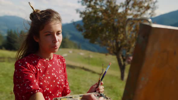Closeup Woman Painter Drawing Picture in Mountains alt