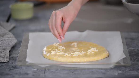Women's Hands Sprinkle Dough with Cheese for Making Khachapuri