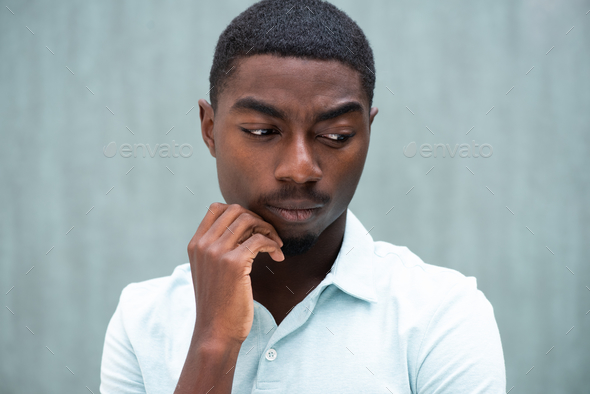 Close up serious young black man thinking with hand to chin