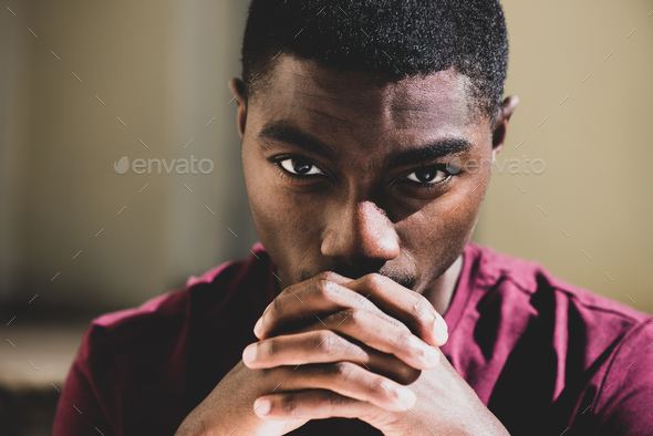 Close up young black man staring with hands clasp