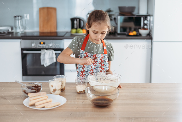 tiramisu making process in the kitchen- little girl making Italian desert with cocoa and espresso-di