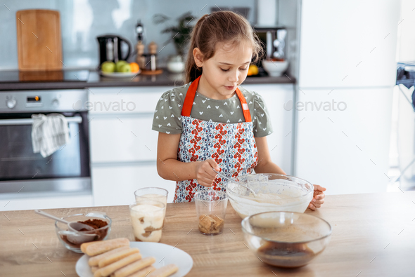 tiramisu making process in the kitchen- little girl making Italian desert with cocoa and espresso-di