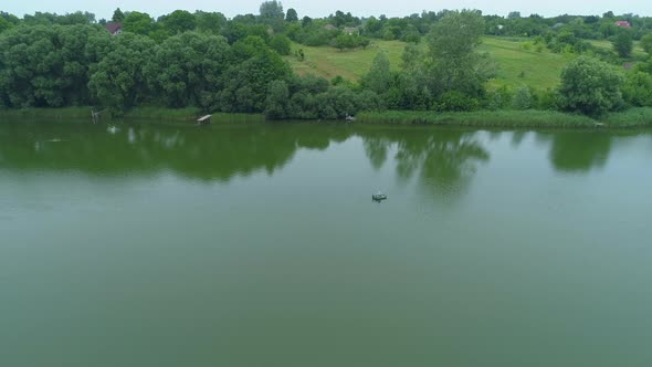 Aerial View Fisherman is Fishing Sitting on an Inflatable Boat in Lake alt