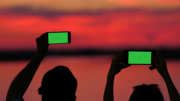 Silhouette of a man and a woman recording videos of the alt