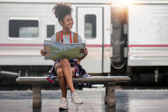 Young woman female smiling traveler with back pack looking to map while waiting for the train at