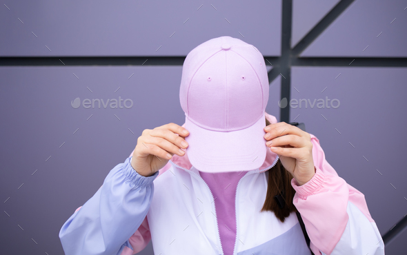 Girl in purple baseball cap on the background of the wall