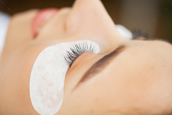 Close-up master of eyelash extensions extends eyelashes to a beautiful woman