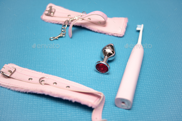 Sex toys on a blue background. Anal plug with pink handcuffs and electric  toothbrush. Household appl Stock Photo by Samio20