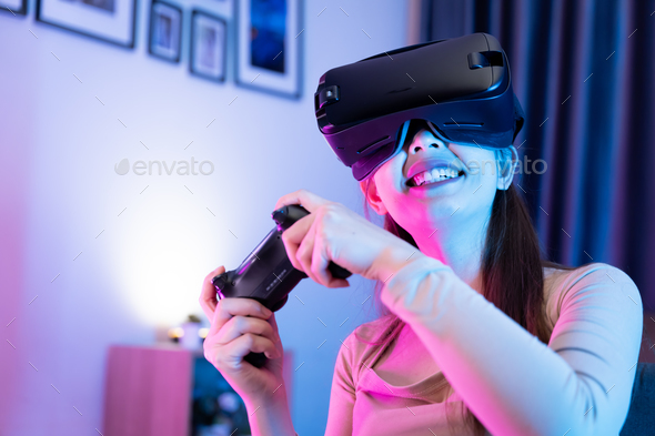 Asian modern female gamer having serious fun playing games from VR console in RGB gaming room.