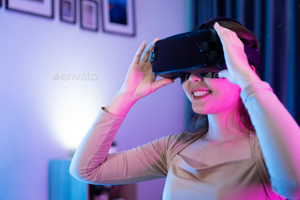 Asian modern female gamer having serious fun playing games from VR console in RGB gaming room.