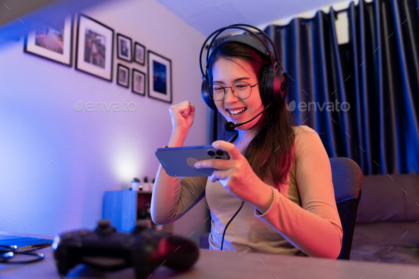 Asian modern female gamer having serious gaming fun in a RGB-lit gaming room.