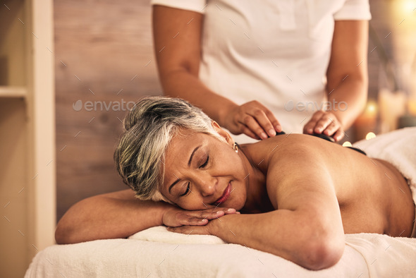 Woman, spa and stone massage for healing back muscle, skincare treatment and holistic therapy at be