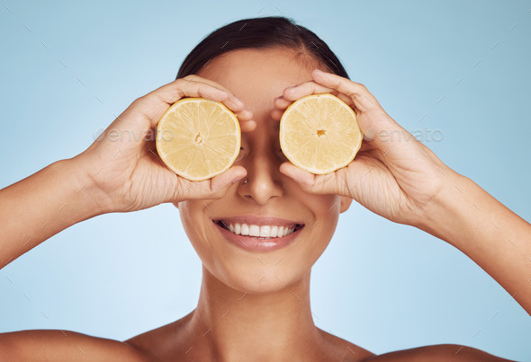 Happy woman, hands and lemon eyes for skincare detox, diet or collagen against a blue studio backgr