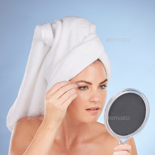 Beauty, woman and mirror with tweezers for eyebrow in studio, blue background or aesthetic change.