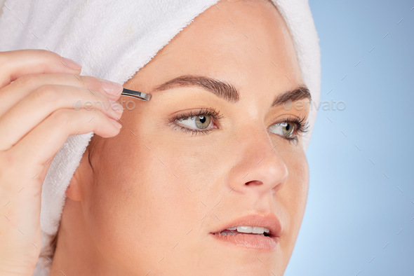 Face, beauty and woman with tweezers for eyebrow in studio, blue background and aesthetic change. C