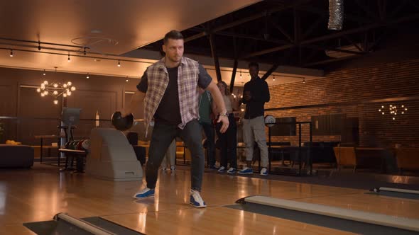 A Man in a Bowling Alley Throws a Ball on the Track and Knocks Out a Shot in Slow Motion and Jumps alt