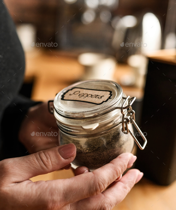 Girl hand opening jar with peppers at kitchen