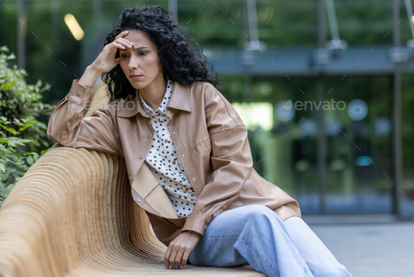 Depressed mature adult woman sitting on bench outside office building, businesswoman boss upset and