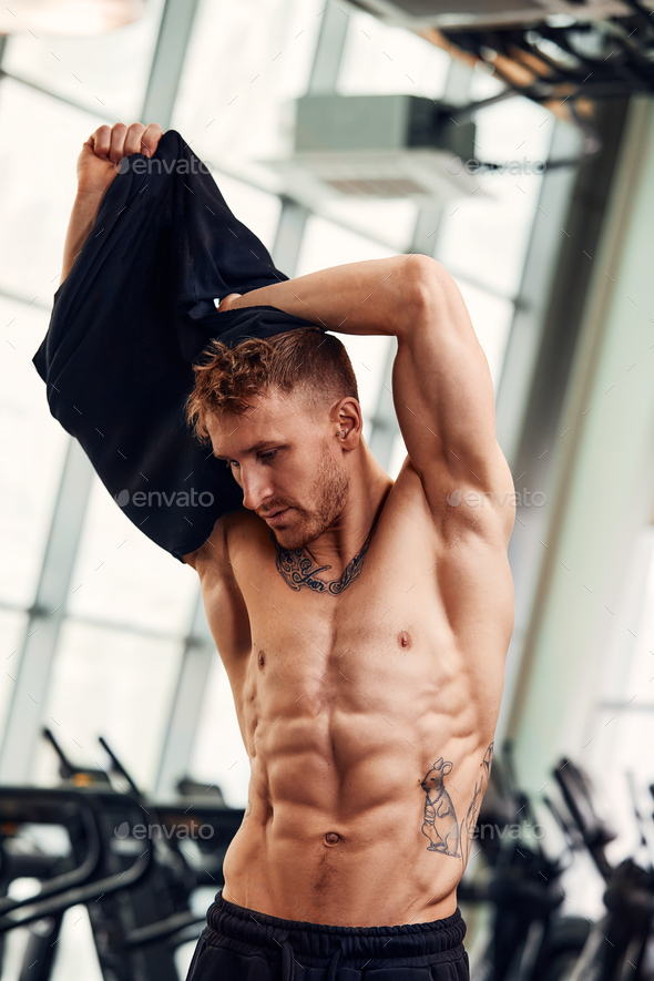 Attractive Bodybuilder Taking His Shirt Off After Training In A Gym