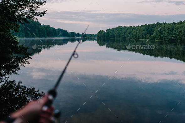 Fisherman with fishing rod, spinning reel on the background river