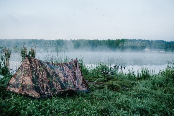 Four carp fishing rods in rod pod on a background of lake and