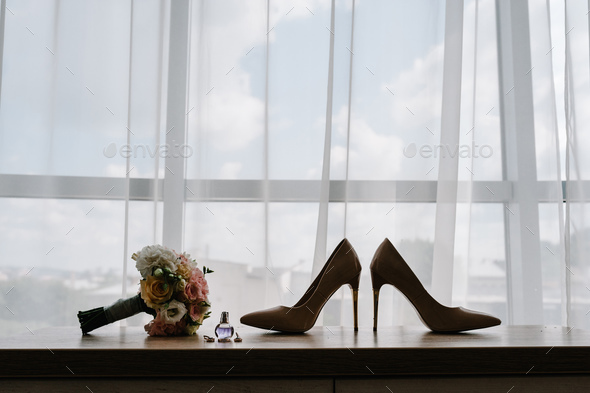 Silhouette on window background. Silhouette of wedding bouquet of the bride, stylish shoes, perfume