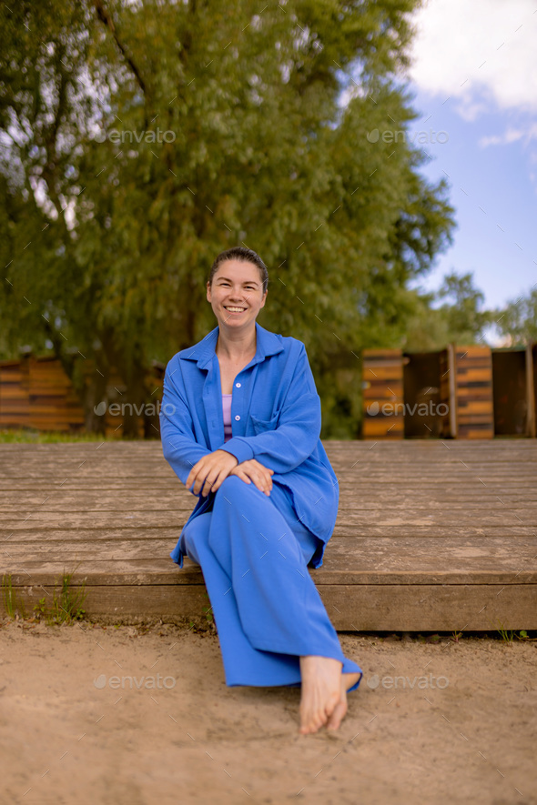 happy woman in wrinkle-free travel clothes enjoy weekend outdoors sitting on wooden embankment