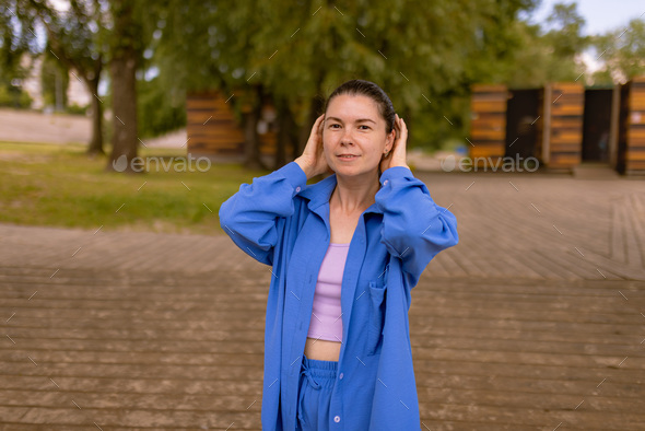 Hairstyle is gathered hair in smooth bun. woman in wrinkle-free travel clothes walking in city park