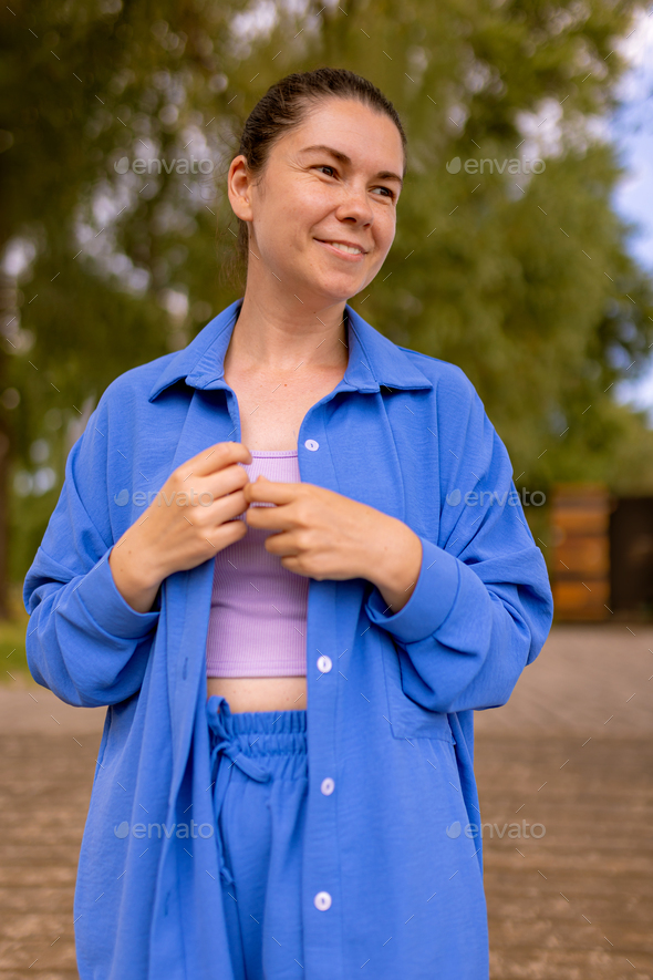 smiling woman in wrinkle-free travel blue clothes walking outdoors and look away, talking to friends
