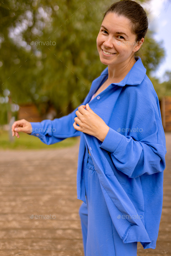 happy woman in wrinkle-free daily clothes shows blue suit advantages outdoors