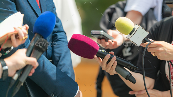 Media coverage as journalists with microphones gather at a press conference