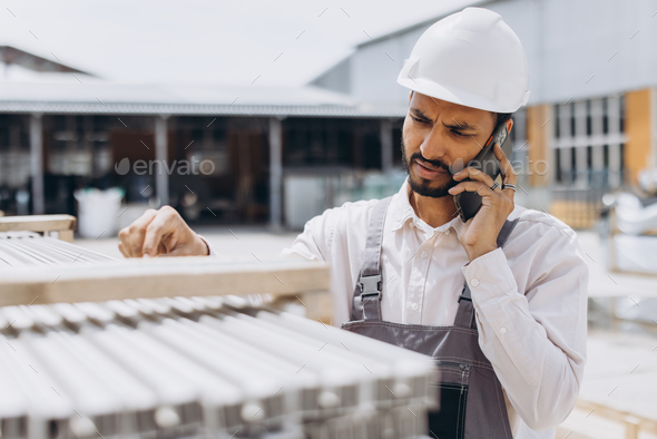 A male Indian manager or staff worker talking by phone and inspecting shipping cargo for import