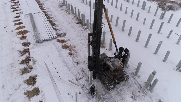 Aerial drone view of a pile bore machine at work at winter construction site 08 alt