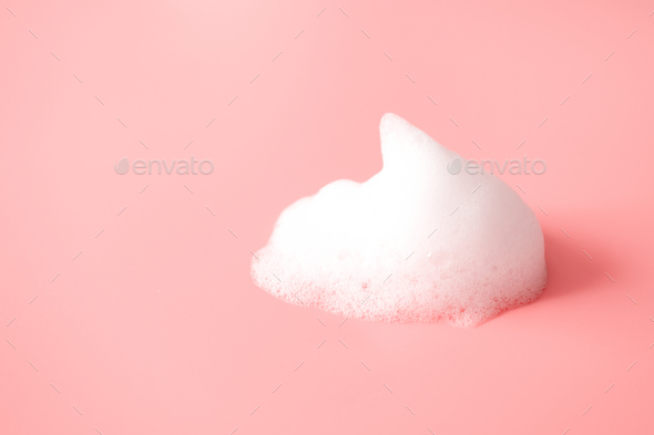 White foam smear from soap, shampoo or cleanser on pink background
