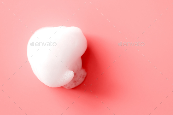White foam smudge from soap, shampoo or cleanser on pink background