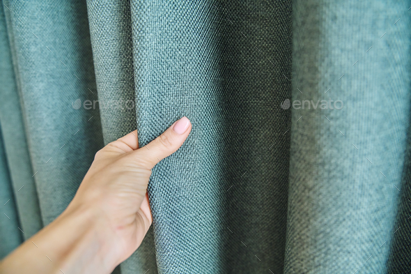 Woman\'s hand touching curtain, green fabric with burlap texture, blackout fabric