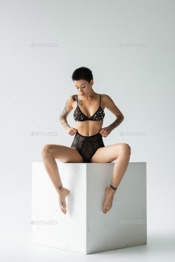full length of provocative and sexy woman with tattooed body and short  brunette hair wearing bra Stock Photo by LightFieldStudios