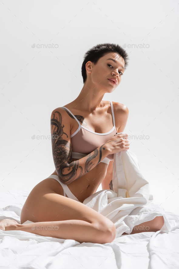 Pretty girl seated on a bed in bra and panties Stock Photo
