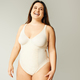 portrait of positive and curvy woman with plus size body posing in beige  bodysuit Stock Photo by LightFieldStudios